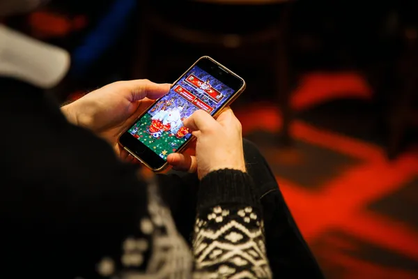 TAKSIM BET Mobil Uygulaması — Casino ve spor için tam merkeziniz Arka planda canlı istatistiklerle dizüstü bilgisayarına odaklanan bir adam, TAKSIM BET mobil uygulamasının spor ve oyun özelliklerini vurgular.